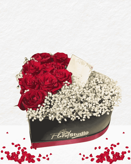 Heart-shaped flower box with red roses and baby's breath, branded 'Floral Studio', on a white background.