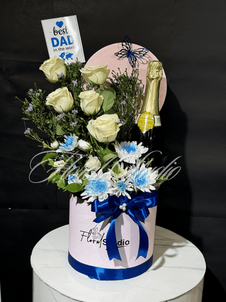 Dad's Delight floral box with white roses, blue flowers, greenery and champagne