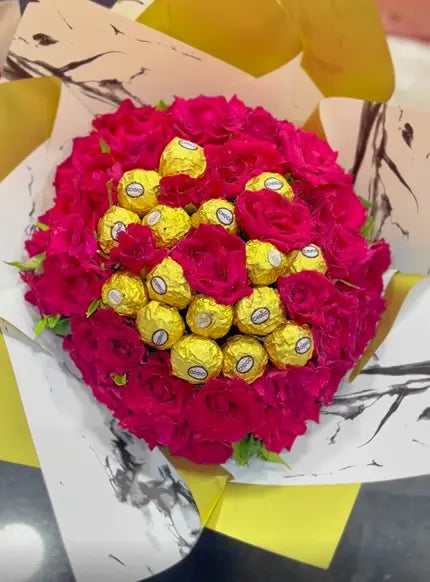 Bouquet of red flowers with chocolate candies in the center on a marble surface. Send flower to Pakistan.