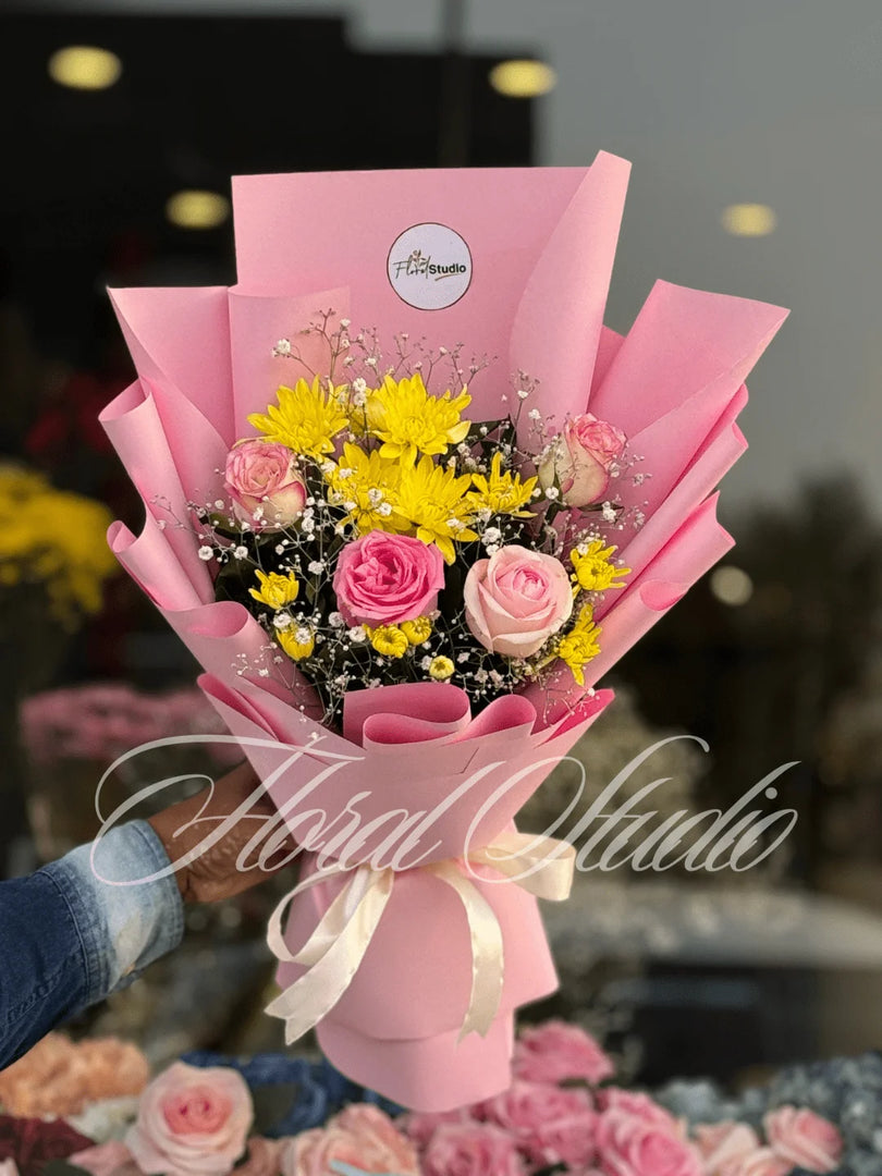 Bouquet of flowers wrapped in pink paper with a blurred background. Send flowers to lahore