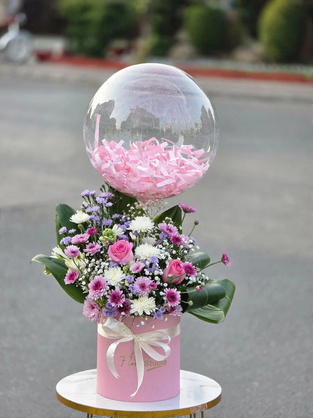 Decorative arrangement with a pink flower-filled balloon on a street background