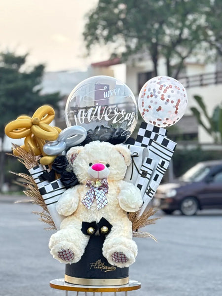 Decorative arrangement with a teddy bear, confetti balloons, chocolate and flowers on a stand outdoors.
Custom Gift Basket