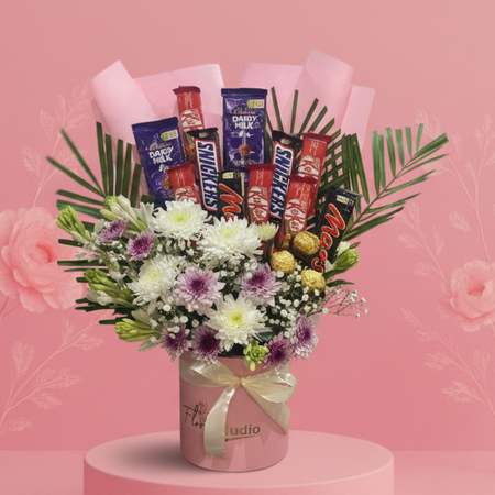 Bouquet of flowers with chocolate bars on a pink platform against a pink background