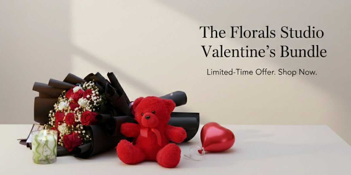 Floral arrangement, red teddy bear, and heart-shaped object on a white surface with 'The Florals Studio Valentine's Bundle' text.