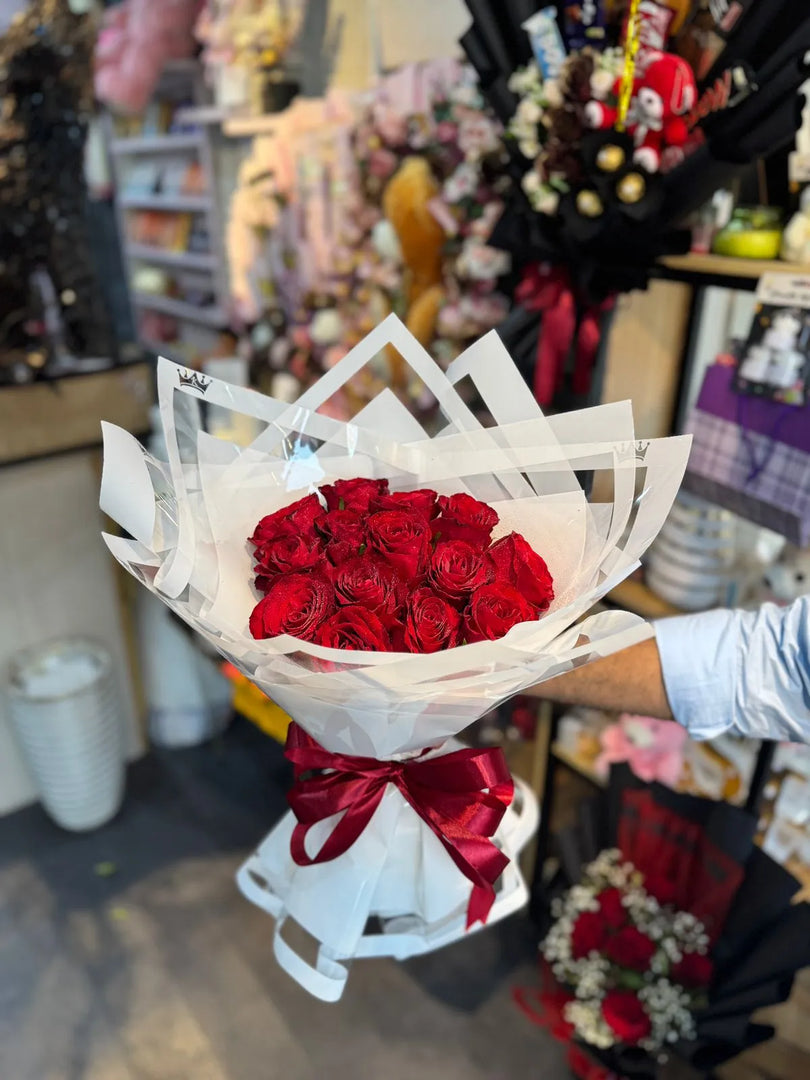 Bouquet of 15 red roses with a white paper wrap and red ribbon . A classical bouquet designed for forgiveness and an apology. 