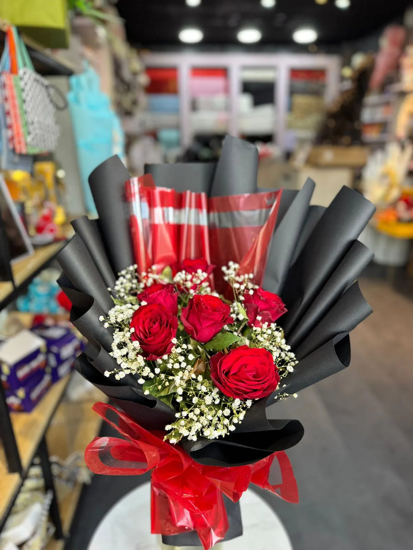 Bouquet of red roses with black and red wrap in a store setting