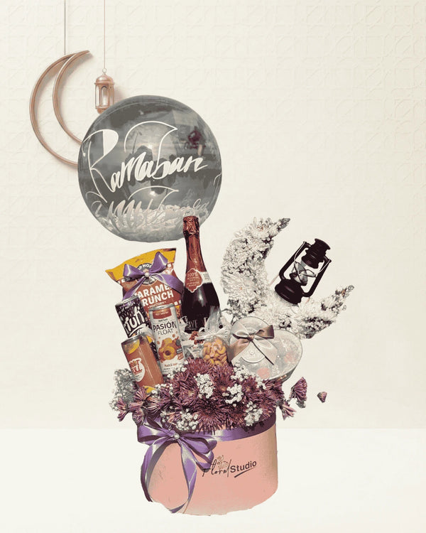 Gift basket with champagne, snacks, and flowers on a light background