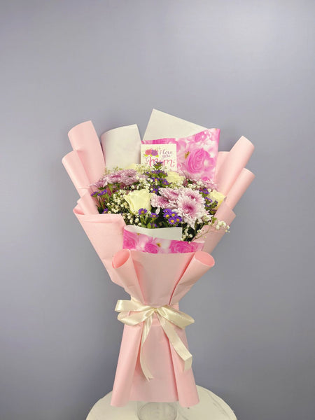 Bouquet of flowers wrapped in pink paper with a card on a gray background. send flowers to lahore