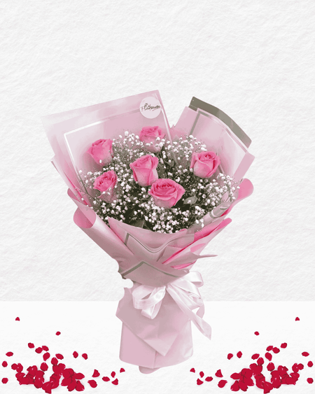 Bouquet of pink roses with baby's breath in pink paper wrapping on a white background