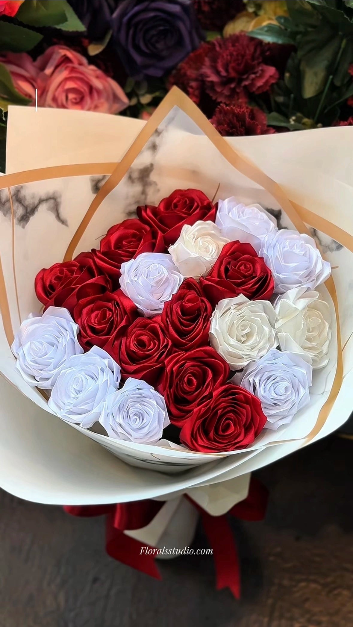 Bouquet of red and white roses in a decorative box with 'Floral Studio' branding.