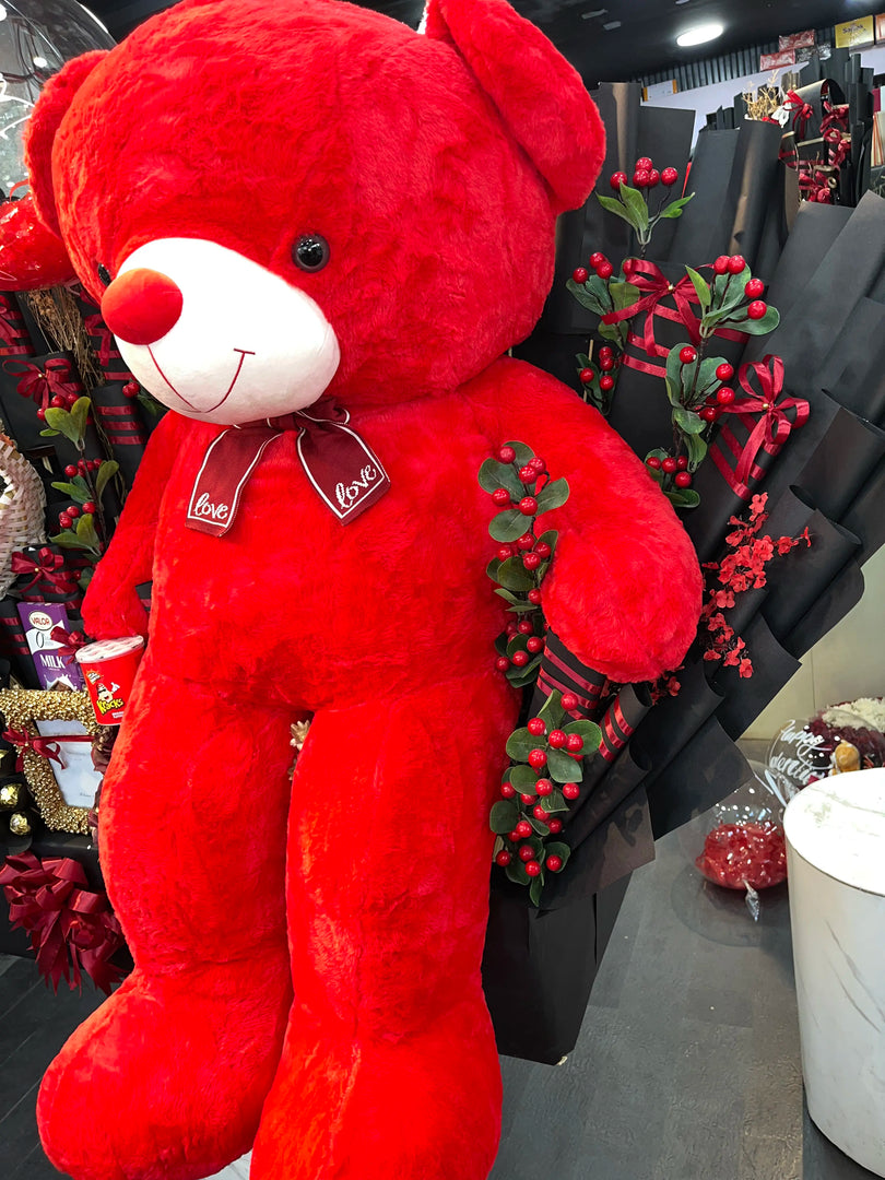 Red teddy bear with 'love' tag in a store setting