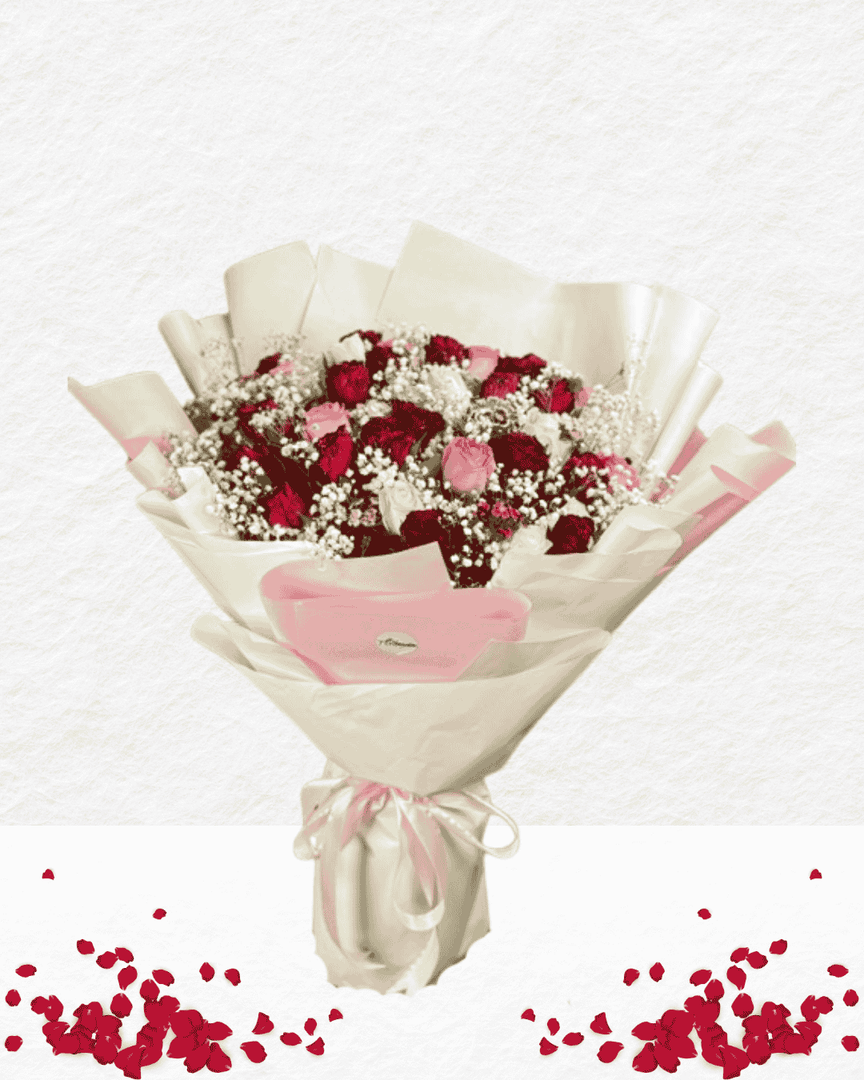 Bouquet of red and pink flowers wrapped in white paper with a pink bow on a white background.