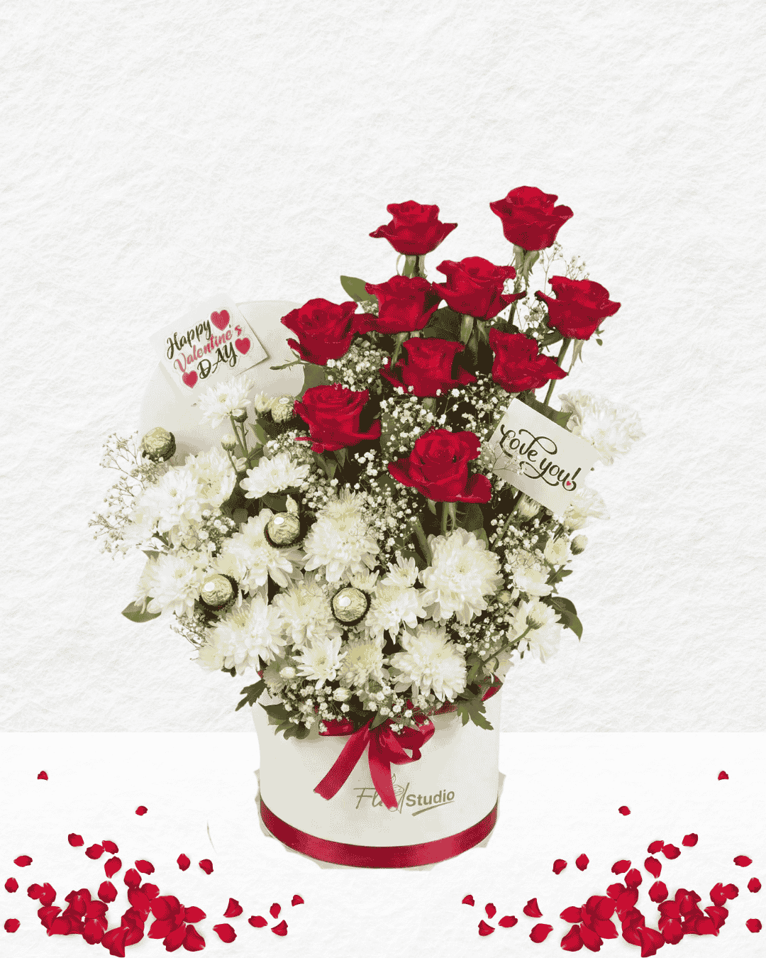 Bouquet of red roses and white flowers in a box with decorative ribbons on a light gray background.