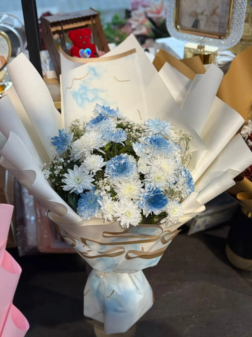 Bouquet of blue and white flowers wrapped in paper with a blurred background
