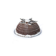 A chocolate ice cream bombe with a brownie dome, draped in chocolate fudge sauce and a vanilla ice cream core, garnished with a chocolate flower on top.