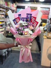 Bouquet of flowers and KitKat chocolate bars wrapped in pink paper with a bow.