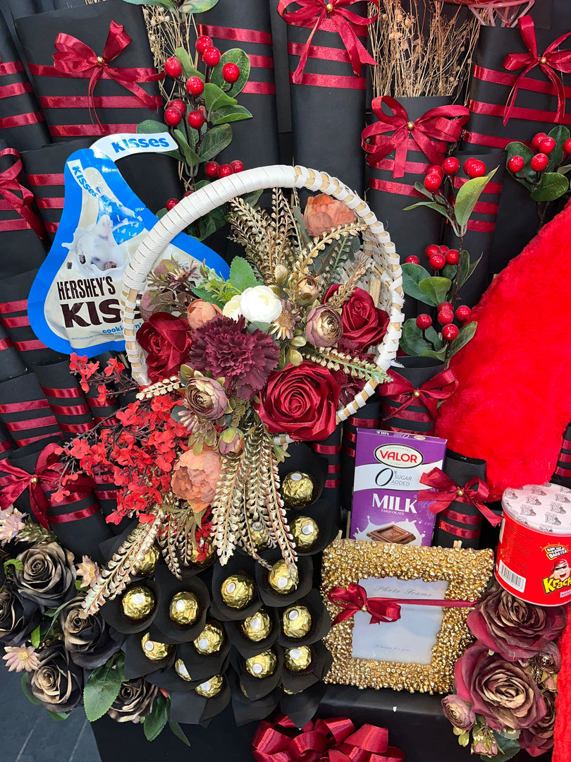 Decorative arrangement with flowers, chocolates, and Hershey's Kisses packaging on a black background.