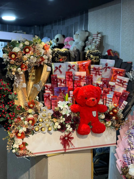 Decorative table with flowers, teddy bear, and gift boxes in a store setting