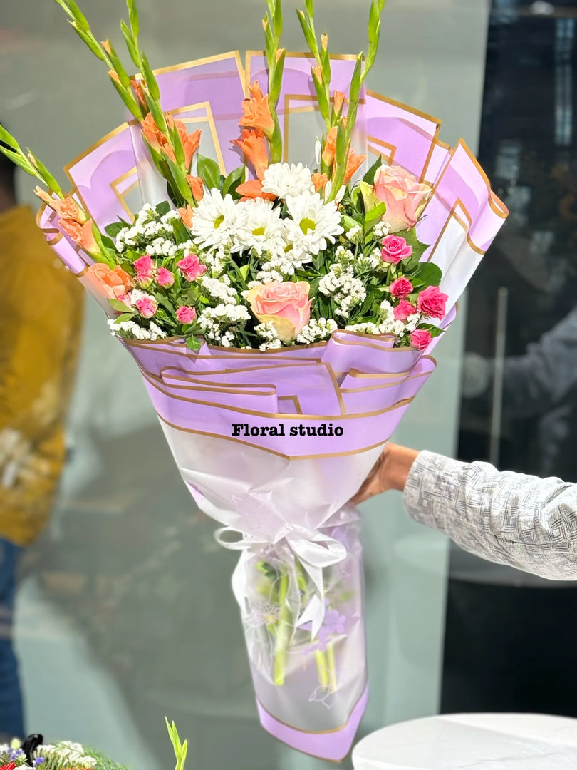 Bouquet of flowers wrapped in purple paper with 'Floral studio' branding. Imported Flower bouquets in Lahore by floral studio