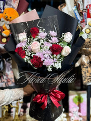 Bouquet of red rosses, pink rosses & purple flowers wrapped in black paper with a red ribbon