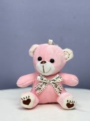 A small pink plush teddy bear with a bow ribbon around its neck.