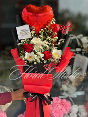 Bouquet with red heart balloon, flowers(red & white rosses), and a card on a blurred background. 