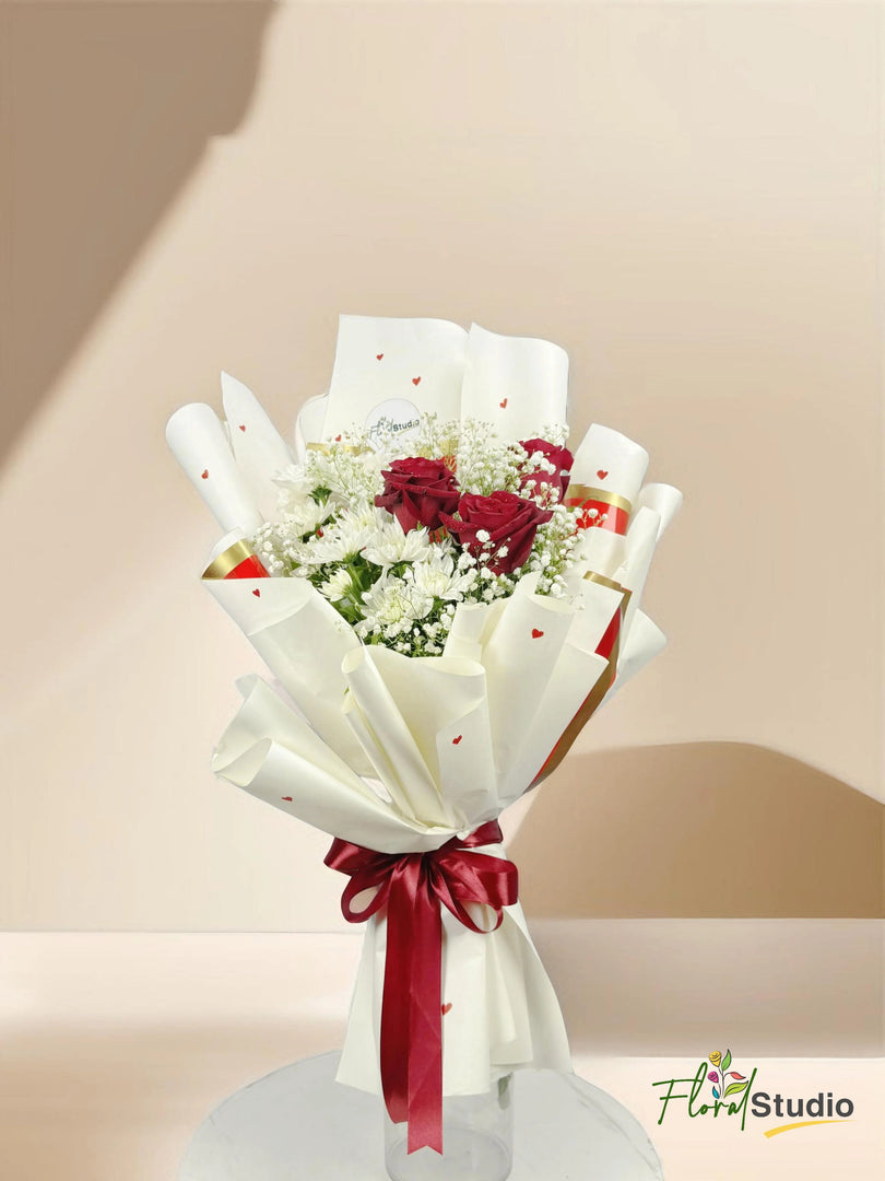 Bouquet of flowers wrapped in white paper with a red ribbon on a beige background, featuring the 'Floral Studio' logo. Send flowers to lahore