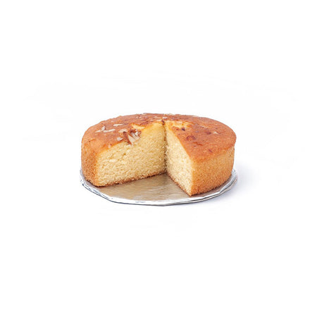 Round plain cake with one slice cut out on metal cooling rack against white background