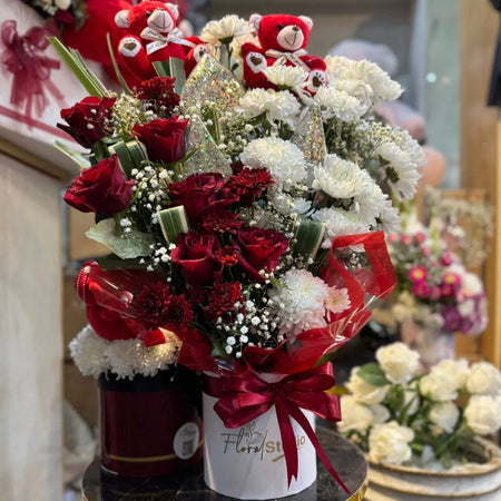 Bouquet of red and white flowers with a decorative bow on a small round table.