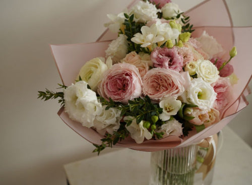 Bouquet of pink and white flowers in a clear vase on a light background