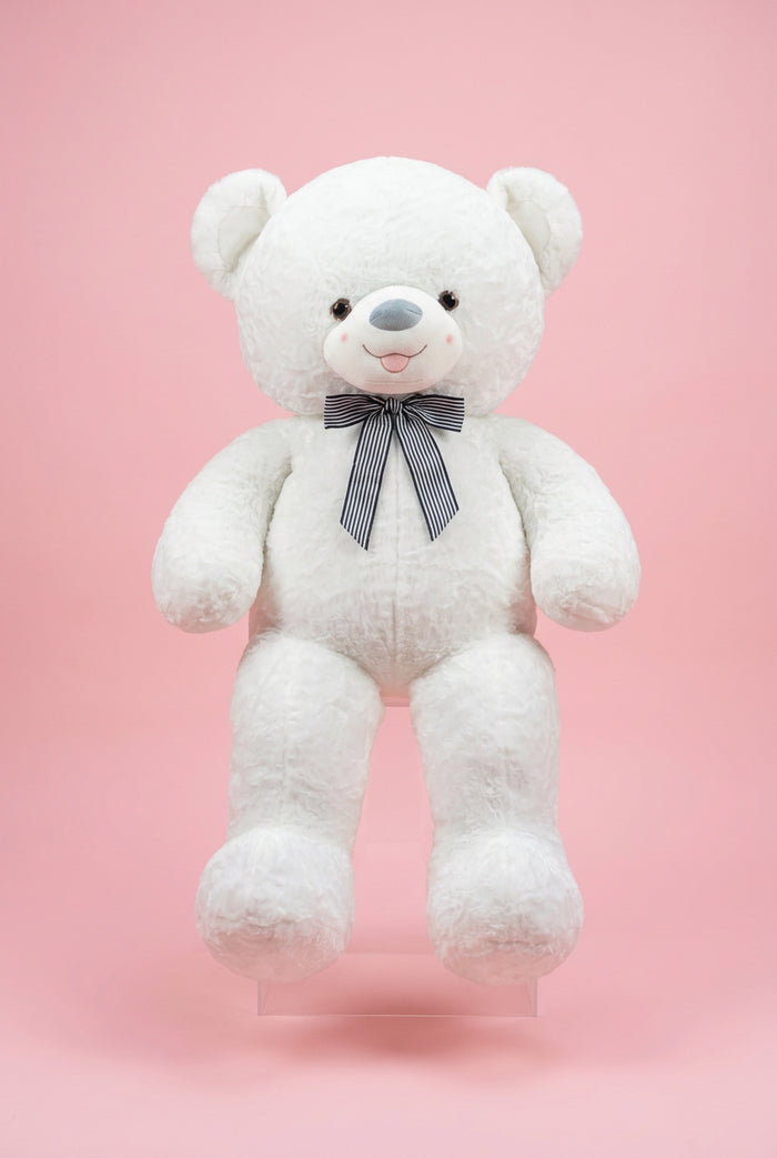 Large white teddy bear with a bow tie in a store setting with flowers and gift bags.