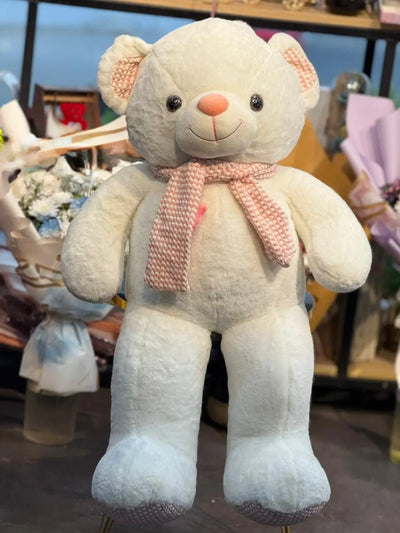 Plush teddy bear with a pink scarf in a store setting