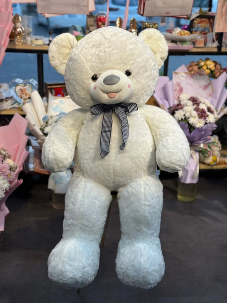 Large white teddy bear with a bow tie in a store setting