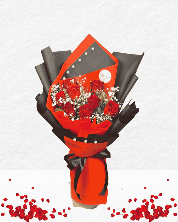 Bouquet of red roses wrapped in black and red paper with a card on a white background