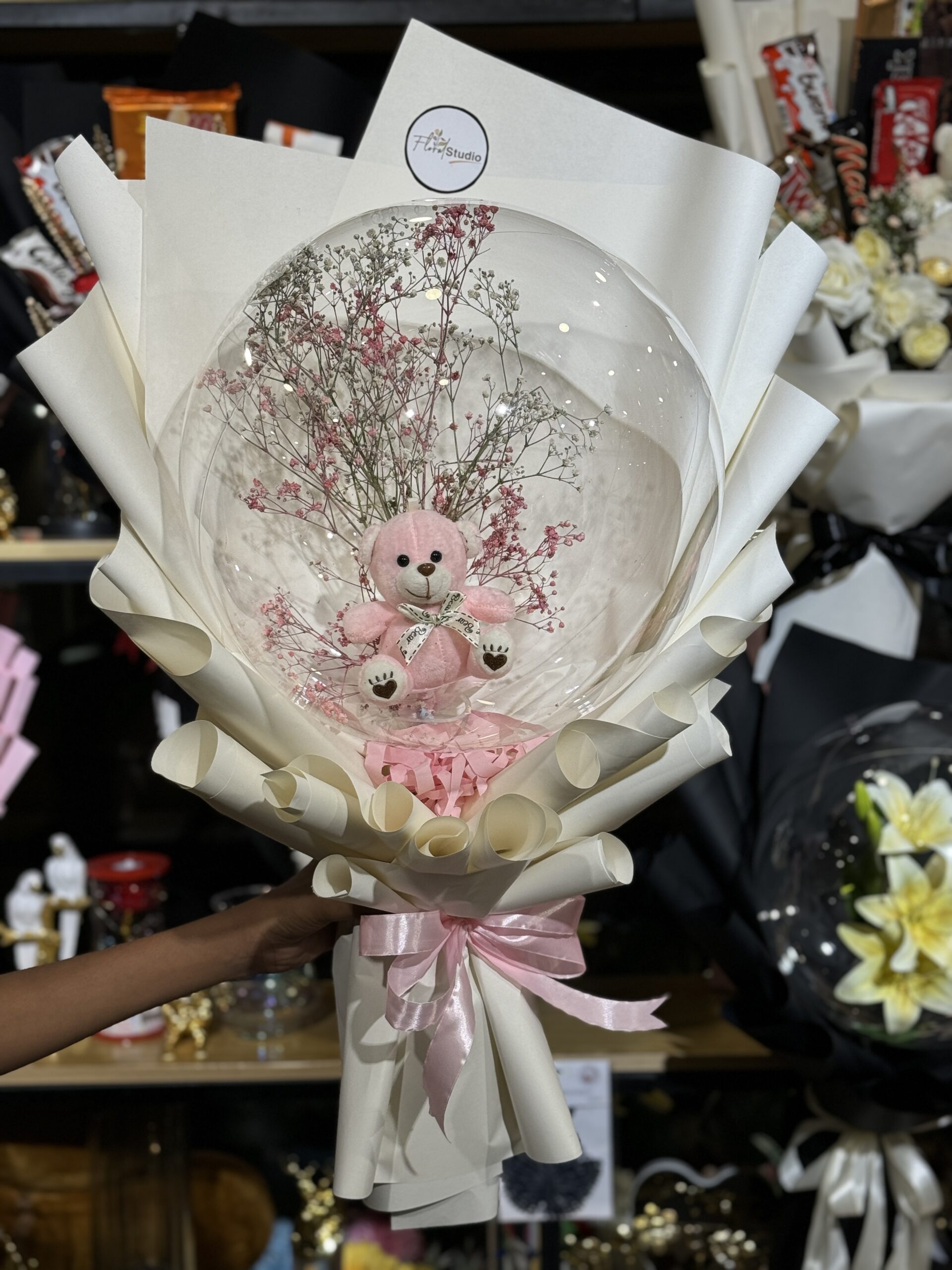 Pink teddy bear inside a clear balloon with baby’s breath flowers, wrapped in elegant white paper and pink ribbon — the Bloom Bear Balloon Bouquet.