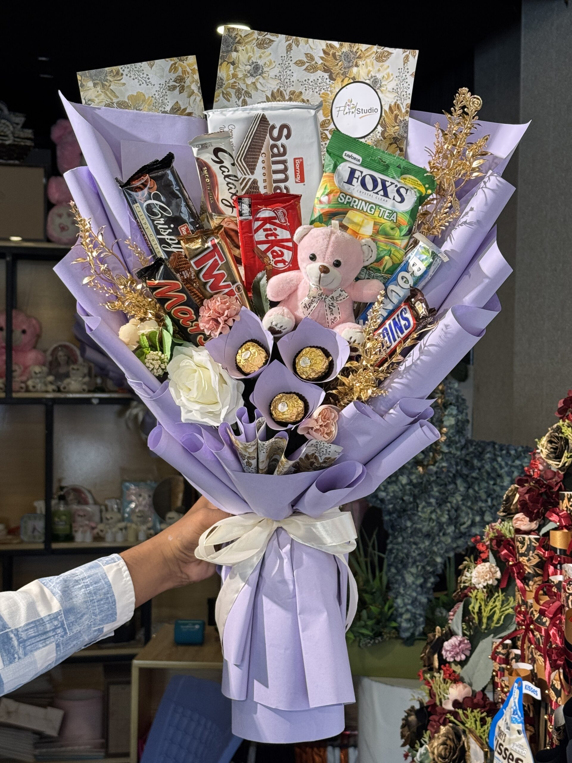 Choco Treat Bouquet with premium chocolates, snacks, and a teddy bear wrapped in elegant purple paper