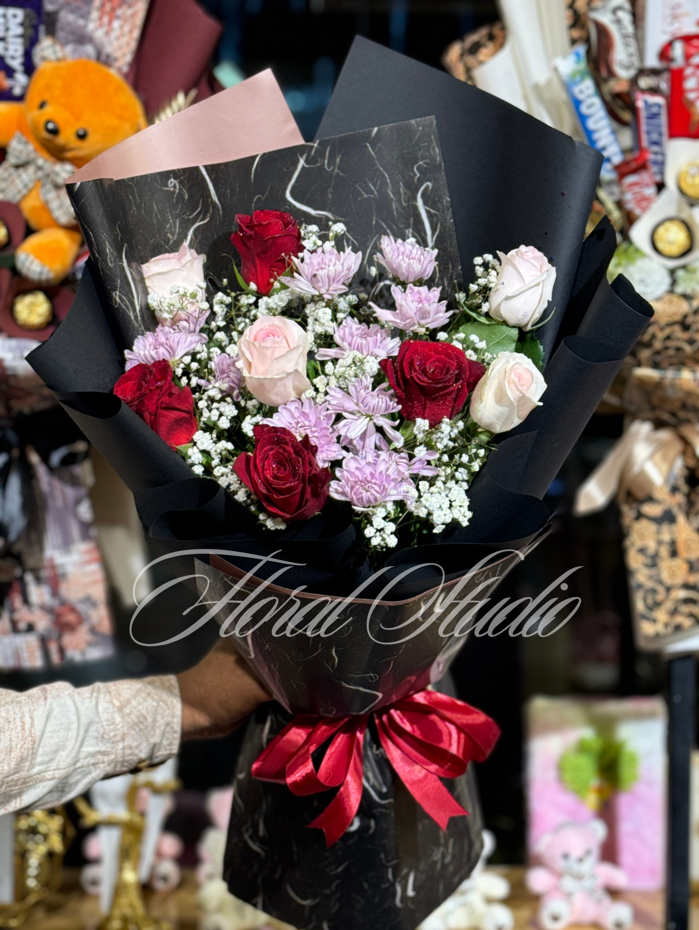 Majestic Bloom luxury bouquet featuring red roses, pink roses, pink chrysanthemums, baby’s breath, and greenery, wrapped in black and marble-patterned paper with a red satin ribbon.