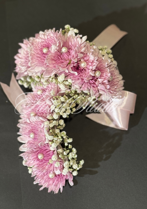 Pink floral gajra with baby’s breath and pearl embellishments, set on a black background.