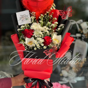 Red Romance bouquet featuring red roses, white flowers, heart-shaped balloon, and butterfly accents wrapped in red and black paper – ideal for anniversaries and romantic gifts.