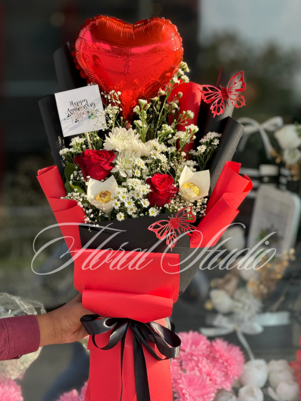 Red Romance bouquet featuring red roses, white flowers, heart-shaped balloon, and butterfly accents wrapped in red and black paper – ideal for anniversaries and romantic gifts.