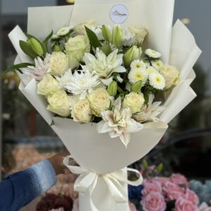 White Peace bouquet with white roses, lilies, chrysanthemums, and dahlias wrapped in elegant white paper for weddings, anniversaries, and sympathy gifts.