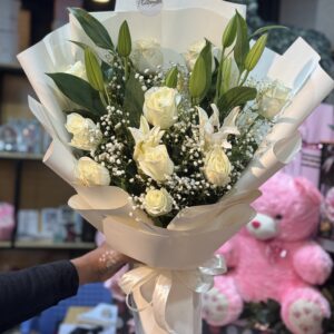 Elegant bouquet of fresh white roses, lilies, and baby's breath, beautifully wrapped in white paper with a satin ribbon, perfect for any occasion. Available for online flower delivery in Lahore.